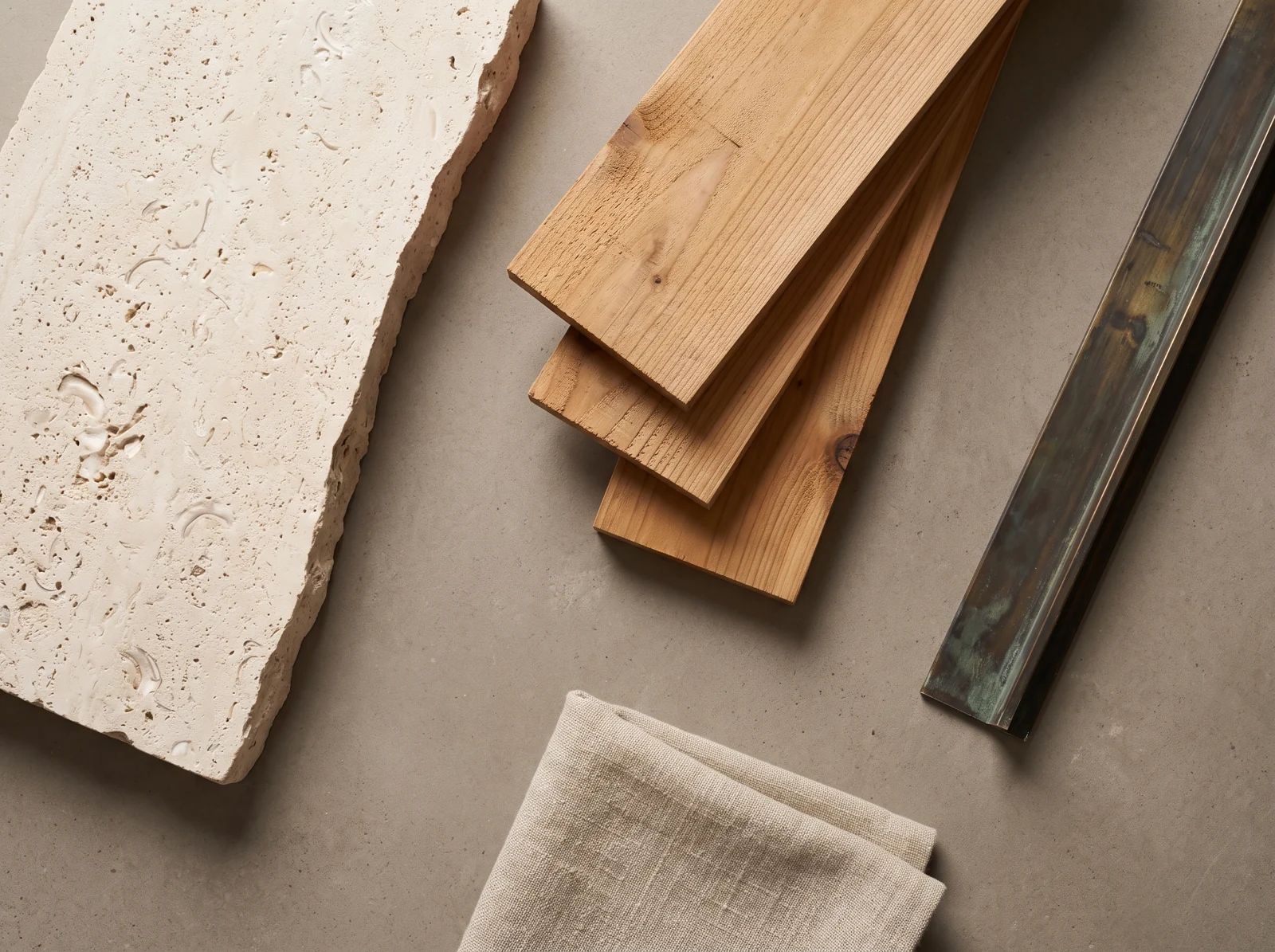 Physical samples of pale limestone, honey-brown cedar, patinated bronze and natural linen on an architect’s worktable.